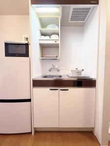 a small kitchen with white cabinets and a sink at The Inui N3 in Tokyo