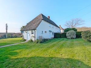 una casa blanca con un gran patio de césped en Southwood Farm Cottage, en West Stoke