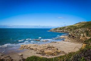 ein Strand mit Menschen im Sand und im Meer in der Unterkunft The Lodge at Hafan Church Bay, Gadlys Coastal Cottages in Llanrhyddlad
