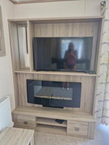 ein großes Entertainment-Center mit einem Flachbild-TV in der Unterkunft The Lodge at Hafan Church Bay, Gadlys Coastal Cottages in Llanrhyddlad