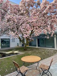 a table and chairs under a tree with pink flowers at hoffmanns höfe in Frankfurt/Main