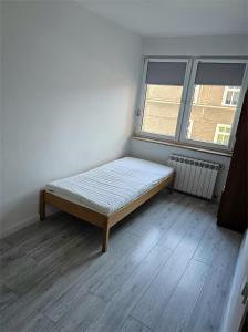 a bed sitting in a room with a window at Apartament Mieszkanie Kamień Pomorski in Kamień Pomorski