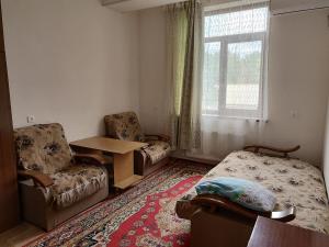 a living room with a bed and chairs and a window at Квартира in Samarkand