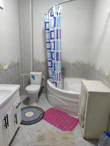 a bathroom with a tub and a toilet and a shower curtain at Квартира in Samarkand