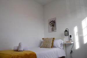 a white room with a bed and a vase of flowers at Domus Citrus in Merida
