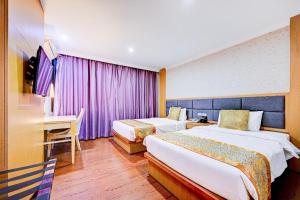 a hotel room with two beds and a desk at Palette The Travellers Hotel Bangkok in Bangkok