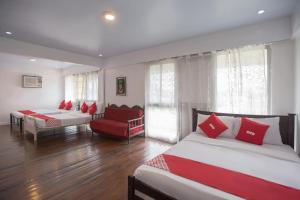 a bedroom with two beds and a red chair at OYO 588 Sunrock Resort in Antipolo +55 photos
