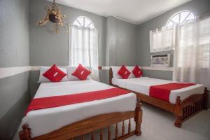 two beds in a room with red and white pillows at OYO 588 Sunrock Resort in Antipolo