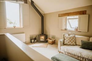 a living room with a fireplace and a couch at Lyme Tree Farm Cottages - Hotching Barn and Knockstone Cottage in Tideswell