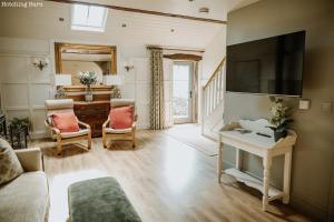a living room with a couch and a tv at Lyme Tree Farm Cottages - Hotching Barn and Knockstone Cottage in Tideswell