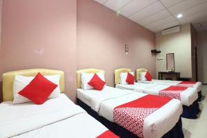 three beds in a room with red and white pillows at Hotel O Destiny Riverside Hotel in Kota Bharu