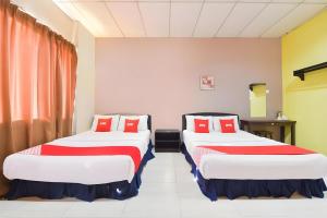 two beds in a room with red pillows at Hotel O Destiny Riverside Hotel in Kota Bharu