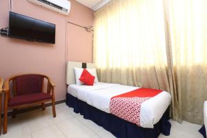 a bedroom with a bed and a tv and a chair at Hotel O Destiny Riverside Hotel in Kota Bharu