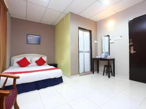 a bedroom with a bed with red pillows and a table at Hotel O Destiny Riverside Hotel in Kota Bharu
