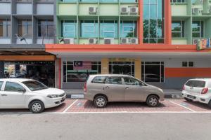 tre auto parcheggiate in un parcheggio di fronte a un edificio di Capital O 89344 Labuan Avenue Hotel a Labuan