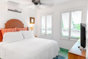 a white bedroom with a bed and windows at Plantation House Trinidad suite in Playa del Carmen
