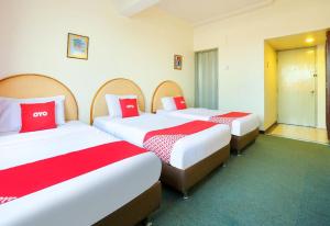 two beds in a hotel room with red and white sheets at Hotel O My Hotel in Segamat