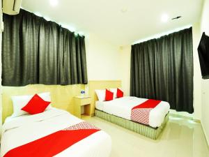 two beds in a room with black curtains and red pillows at OYO 1055 Batu Caves Star Hotel in Batu Caves +39 photos