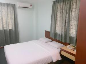 a bedroom with a white bed and a window at Hotel O Asia City in Kota Kinabalu