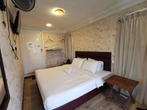 a bedroom with a large white bed and a table at Hotel O Mount Hill Villa Kundasang in Ranau