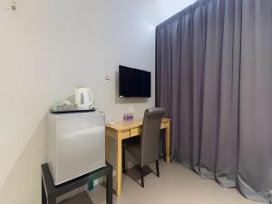 a room with a desk with a computer and a television at Yootel Boutique Hotel in Kajang