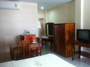 Habitación con cama, TV y muebles de madera. en Ratchaphruek Resort en Lop Buri