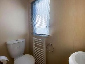 Un baño con inodoro, lavabo y ventana. en Homely 8 Berth Caravan With Side Decking And Ramp Access In Kent, Ref 47018H, en Whitstable