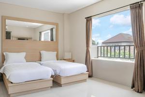 two beds in a bedroom with a large window at Collection O Kuta Near Airport Ngurah Rai in Kuta