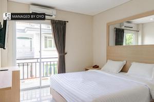 a bedroom with a bed and a large window at Collection O Kuta Near Airport Ngurah Rai in Kuta