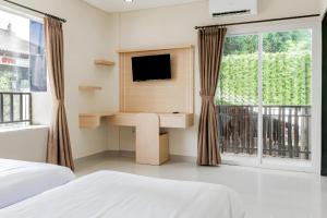 a bedroom with a desk and a tv and a window at Collection O Kuta Near Airport Ngurah Rai in Kuta