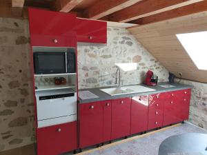 a red kitchen with a sink and a microwave at Magnifique Gite de charme in Seyssel