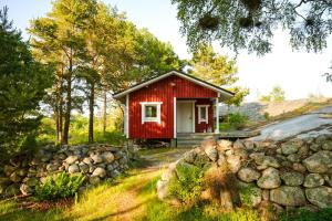 a red cottage in the woods with a stone wall at Sandholm Cottage in Nötö