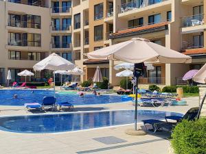 a swimming pool with umbrellas and chairs and a hotel at Apartments Obzor Beach C - Апартаменти Обзор Бийч С in Obzor