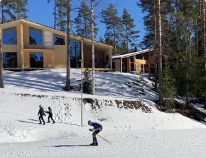 two people skiing in the snow in front of a house at Havu Resort Laajavuori - Luksushuvila keskellä suomalaista metsää, Jyväskylä in Jyväskylä