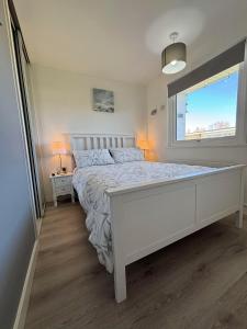 a bedroom with a white bed and a window at 169 Sunbeach, Scratby - Two bed Chalet, sleeps 5, pet friendly, FREE pool and entertainment passes plus WiFi and linen and towels included in Great Yarmouth