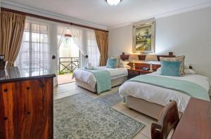 a bedroom with two beds and a table and a window at Afrique Boutique Hotel O.R. Tambo in Boksburg +53 photos