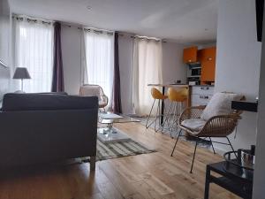 a living room with a couch and chairs and a kitchen at Appartement la défense Courbevoie in Courbevoie