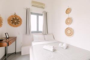 a white bedroom with a bed with towels on it at Seven Grapes - Karterados in Karterados