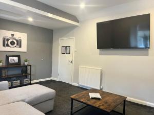 a living room with a couch and a tv on the wall at Laurel Bank Hotel in Markinch