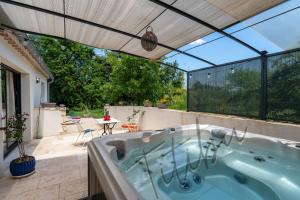 een hot tub op een patio met een dak bij Le Titibu, Gîte et Spa entre Ardèche et Provence, Clim, BBQ, Netflix, classé 5 étoiles in Saint-Paulet-de-Caisson