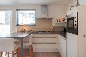 a kitchen with white cabinets and a table with chairs at Garden House Harry in Zandvoort