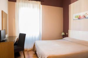 a bedroom with a bed and a desk and a window at Hotel Panorama in Florence