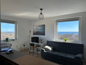 a living room with a couch and two windows at Panorama Bałtyku in Sopot