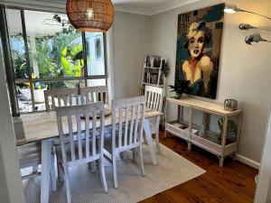 a dining room with a table and chairs and a painting at Frogs by the Sea in Cronulla