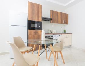 a kitchen with a glass table and white chairs at Magnifique 2 pièces rénové aux Sources in Vieux Kouba