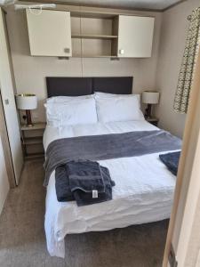 ein Schlafzimmer mit einem Bett mit weißen Laken und Kissen in der Unterkunft The Lodge at Hafan Church Bay, Gadlys Coastal Cottages in Llanrhyddlad