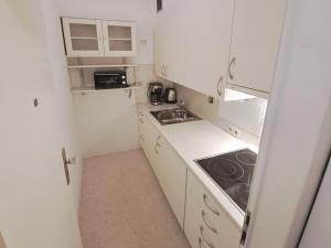 ミュルハイム・アン・デア・ルールにあるApartment with Balcony in Mülheim an der Ruhrの白いキャビネットとシンクを備えた小さなキッチン