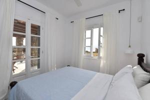 Un dormitorio blanco con una cama y dos ventanas. en Cycladic home in Kampos by GHH, en Kampos