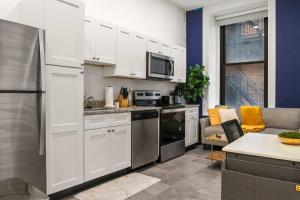 Una cocina con gabinetes blancos y electrodomésticos de acero inoxidable. en CozySuites Stunning 1BR in Downtown Pitts #6, en Pittsburgh 5 fotos más