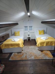 a bedroom with two beds with yellow sheets and a rug at AL Boca da Canada in Água de Alto